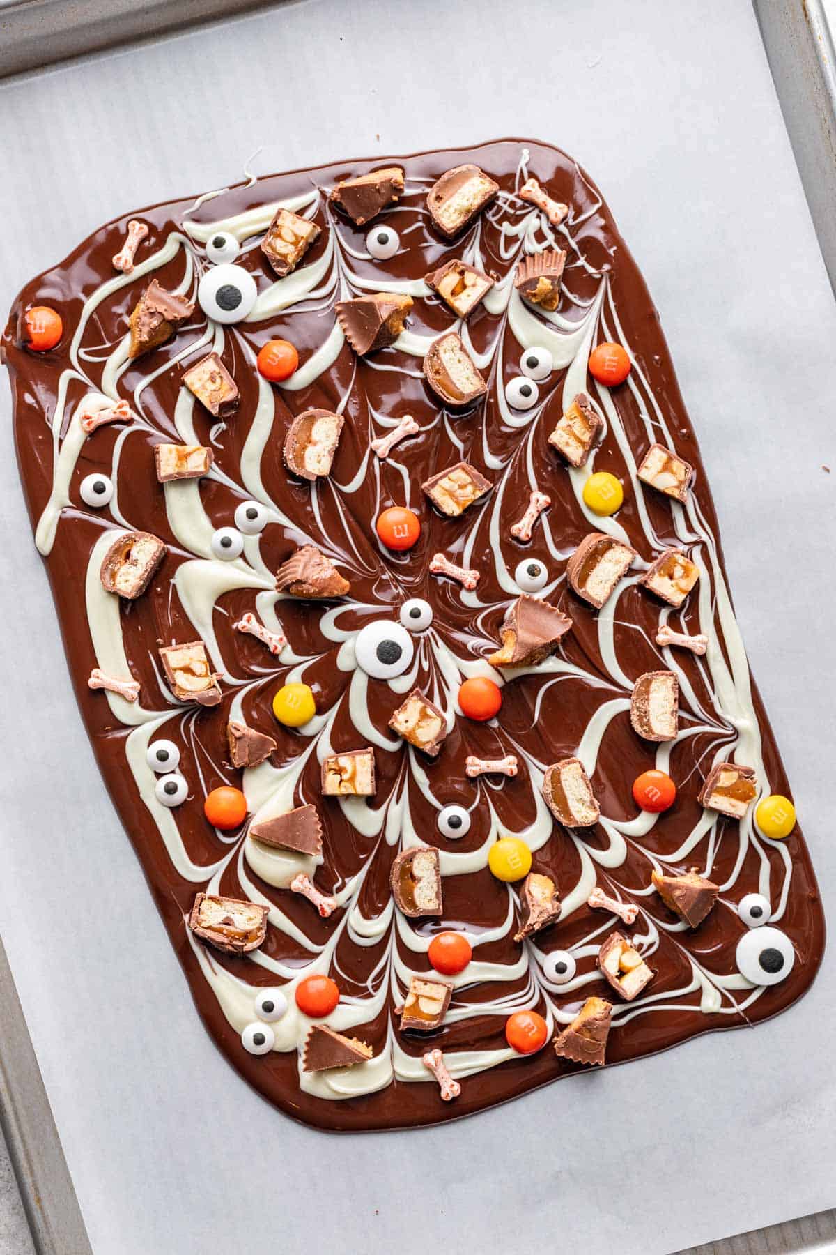 Chopped candy bars, m&ms, and candy bones and eyes on Halloween bark.
