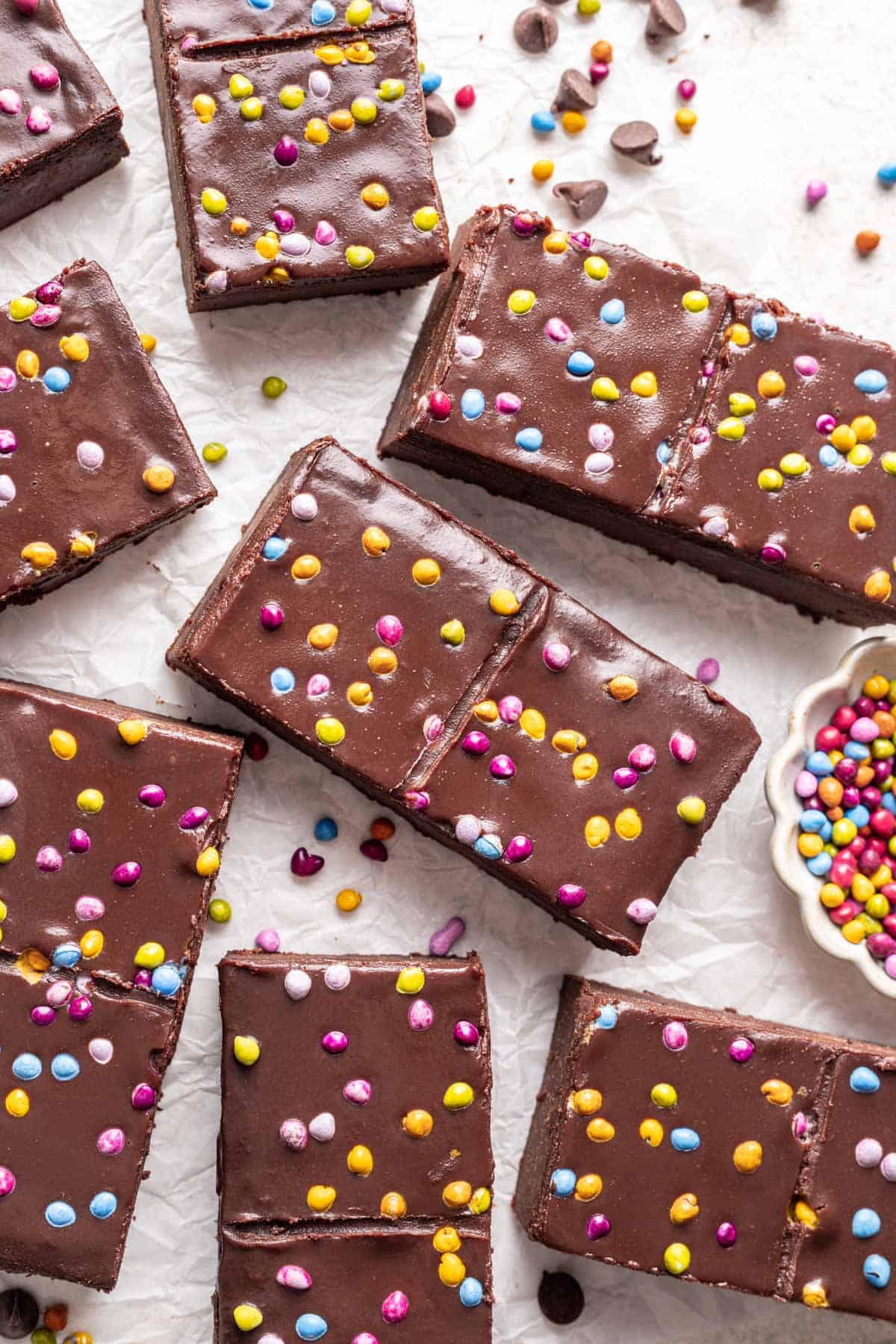 Homemade cosmic brownies with no refined sugars scattered on a white backdrop.