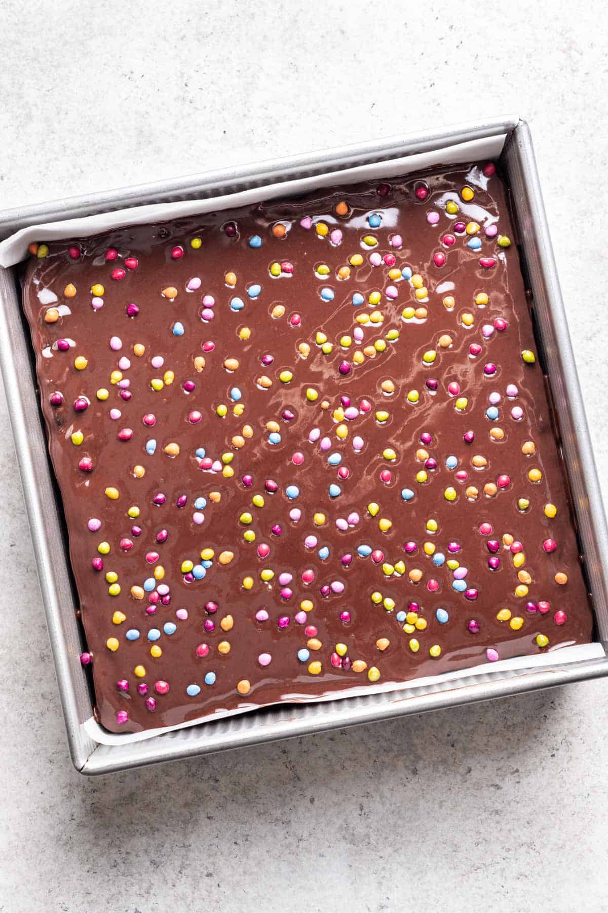 Chocolate topping spread on top of brownies, then sprinkled with colored chocolate chips.