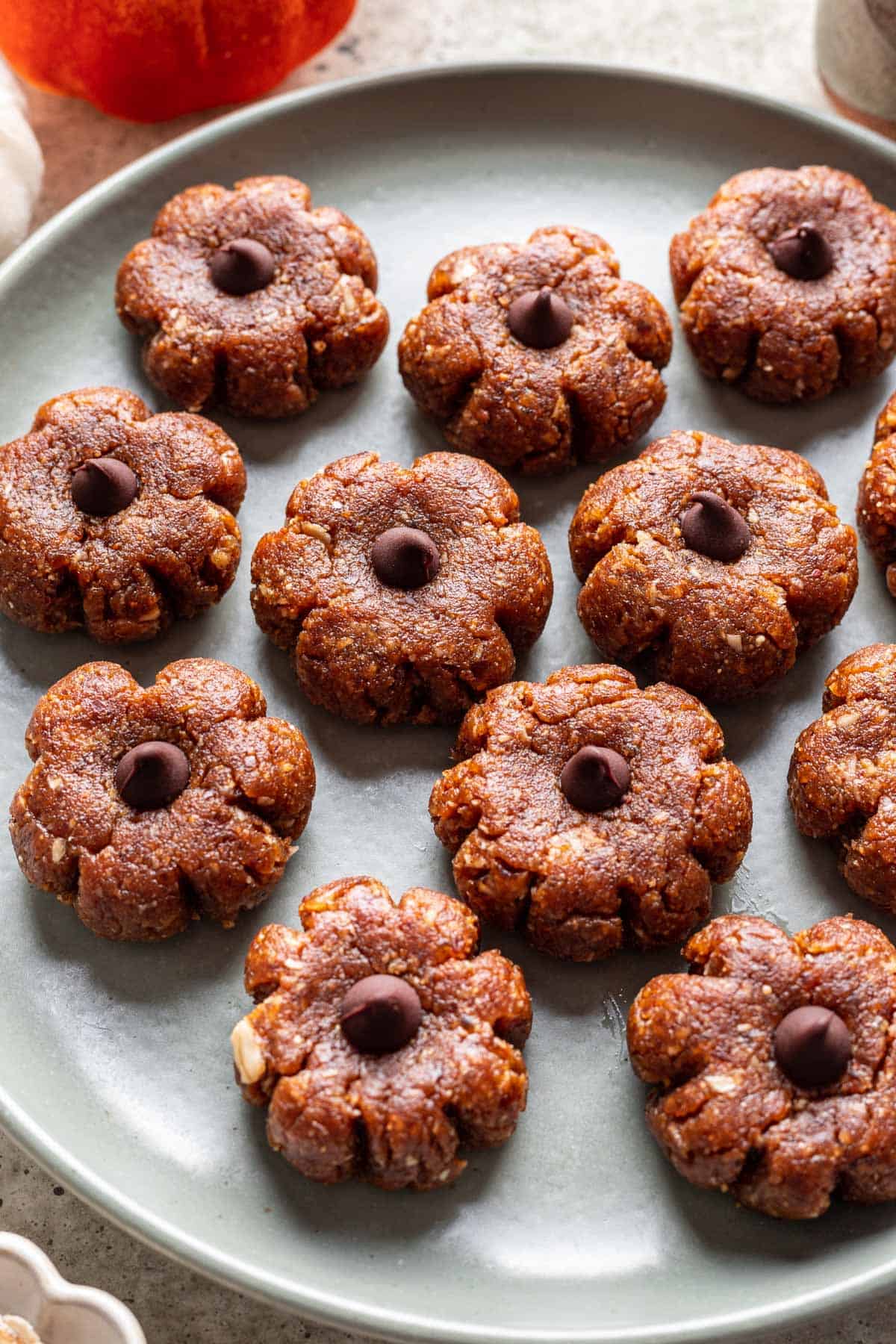 Pumpkin-shaped bliss balls on a serving platter with a chocolate chip on top as a stem.
