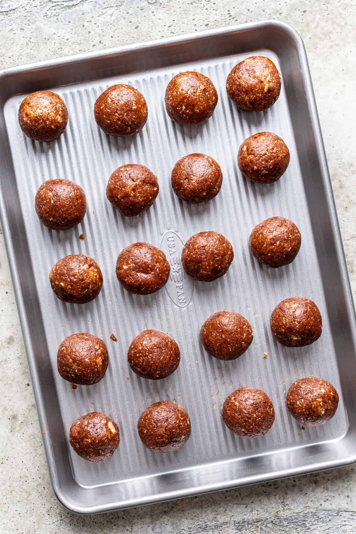 Pumpkin bliss balls rolled into small balls on a baking sheet.