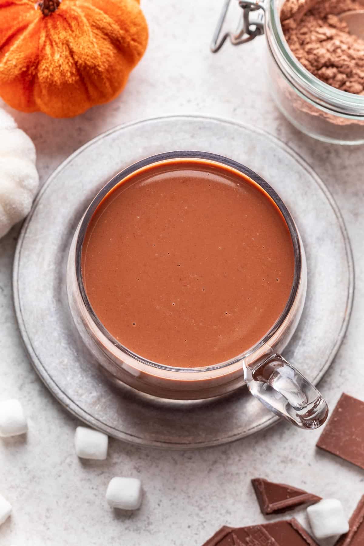 Pumpkin spice hot chocolate on a silver trivet.
