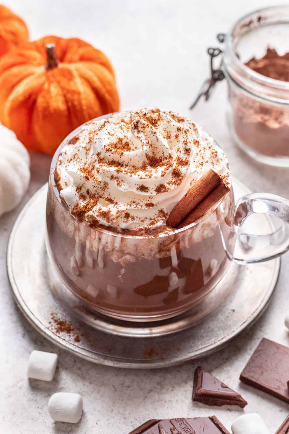 Pumpkin spice hot chocolate topped with whipped cream in a glass mug.