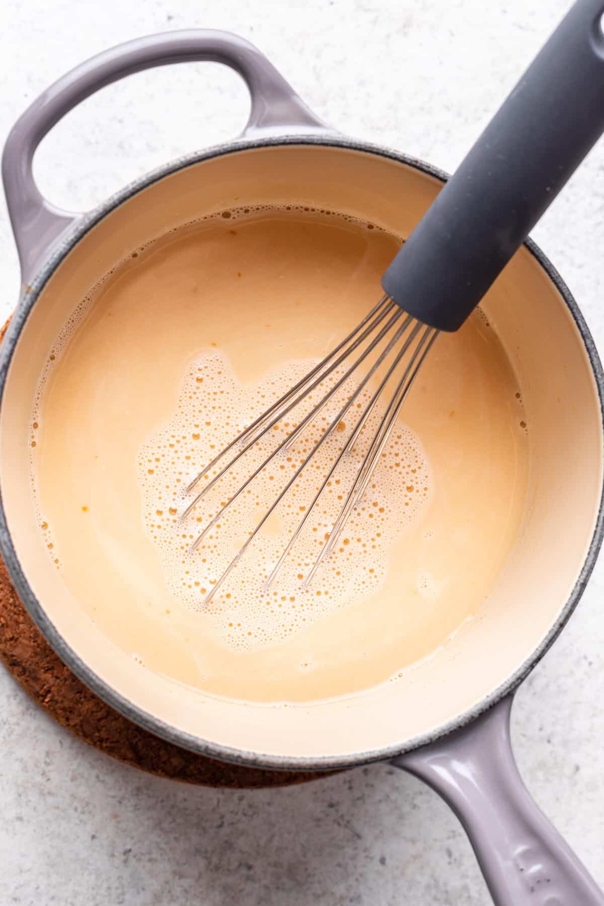 Pumpkin puree added to the heated milk in the saucepan.