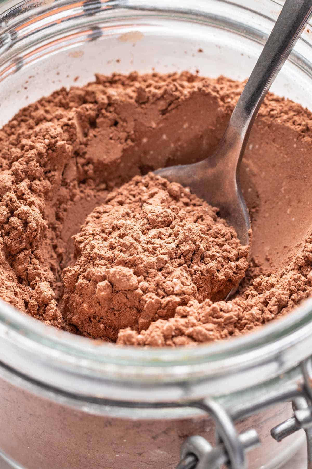 Homemade pumpkin spice hot cocoa mix scooped by a spoon in a jar.