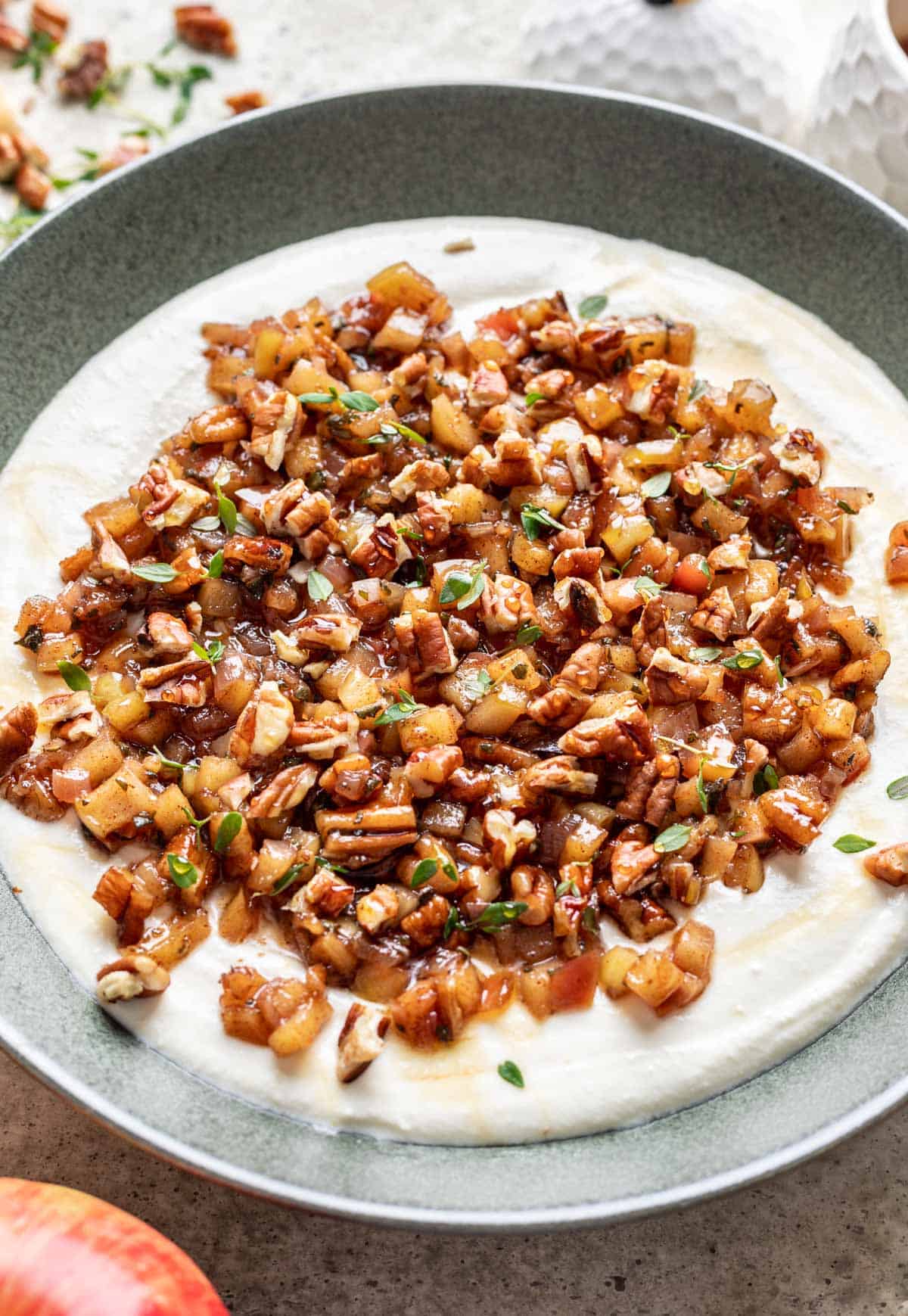 Whipped feta in a bowl, topped with apples, pecans, thyme, and honey.
