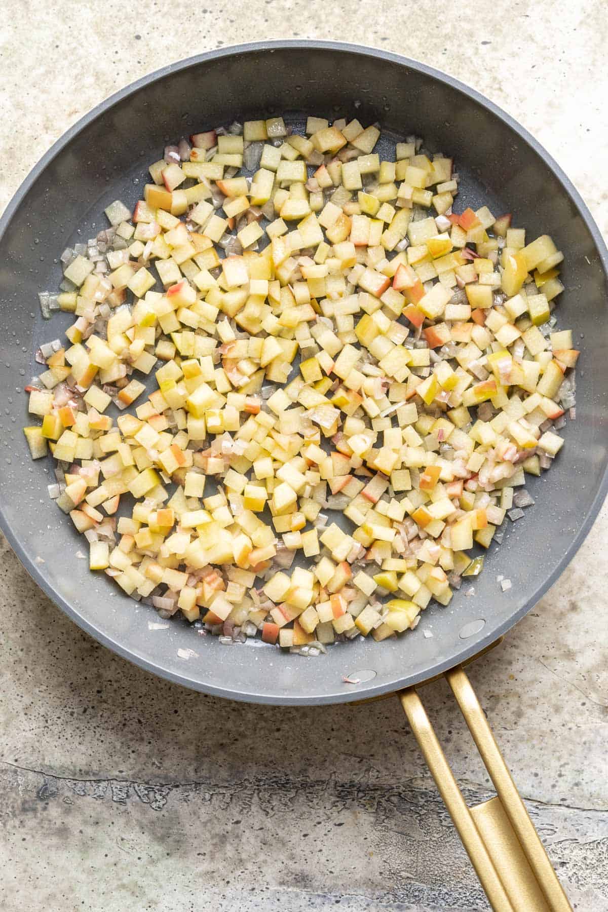 Apples and shallots sautéed in a skillet.