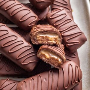 Homemade milky way bars stacked on top of each other with one split in half to show the nougat and caramel inside.