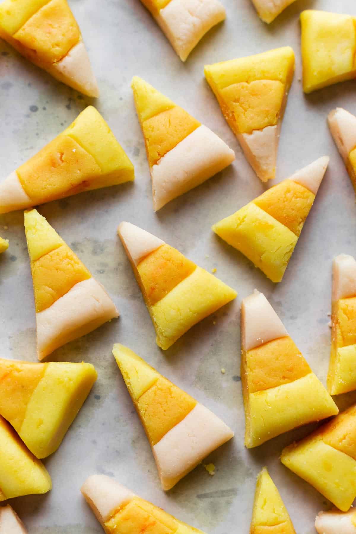 Homemade, dye free candy corn scattered on a gray surface.