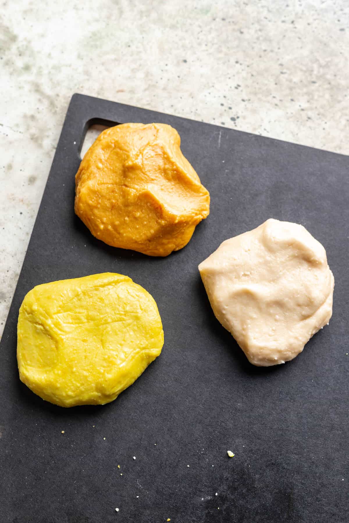 Candy corn dough divided into 3 parts, one colored orange, one colored yellow, and one remains white.