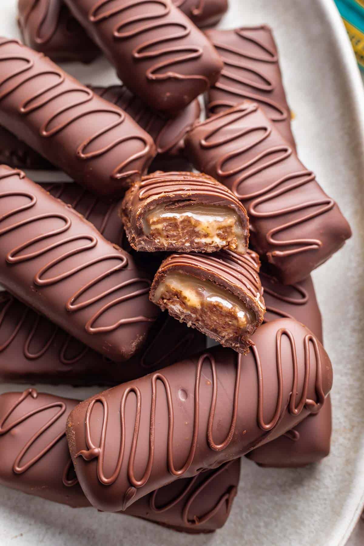 Homemade milky way bars stacked on top of each other with one sliced in half to show the nougat and caramel inside.