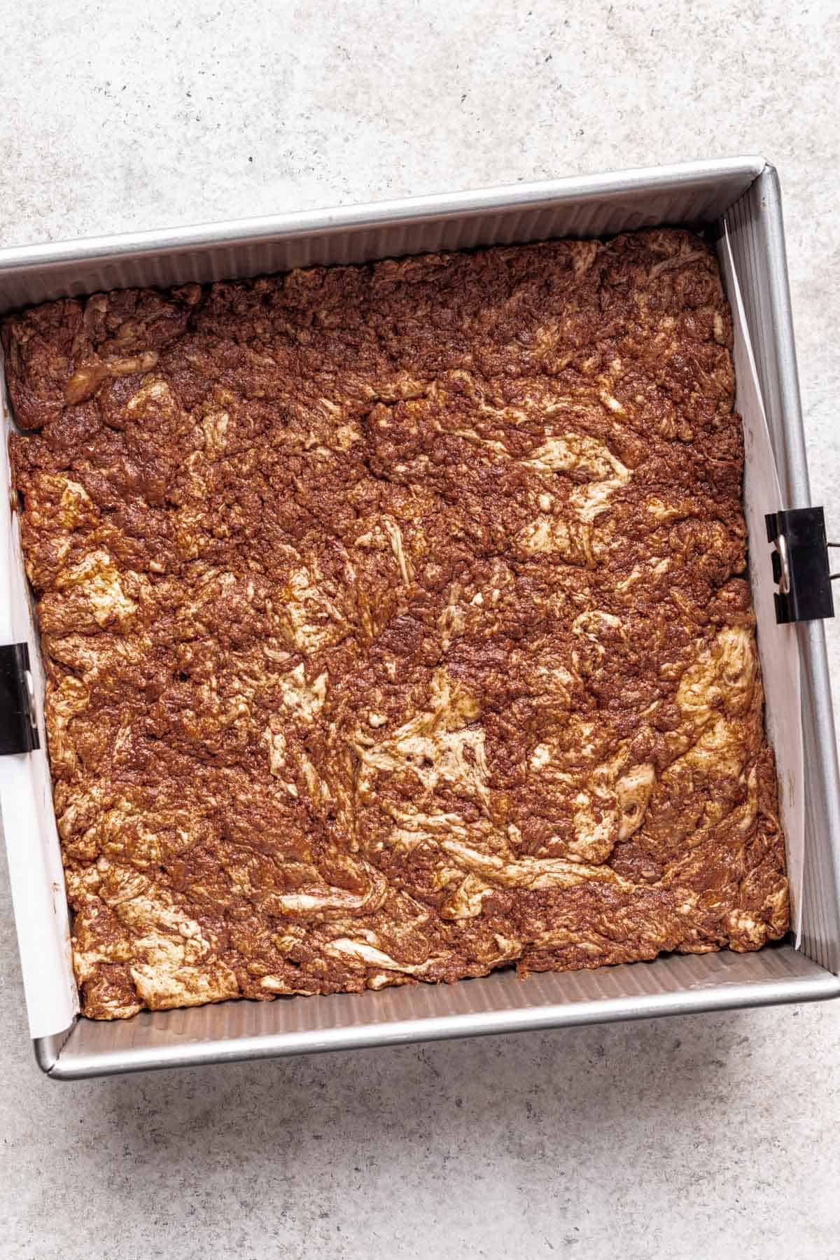 Marshmallow and chocolate mixture pressed into a square baking pan.