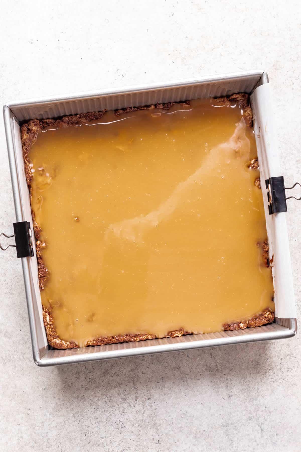 Caramel spread on top of homemade marshmallow nougat in a baking pan.
