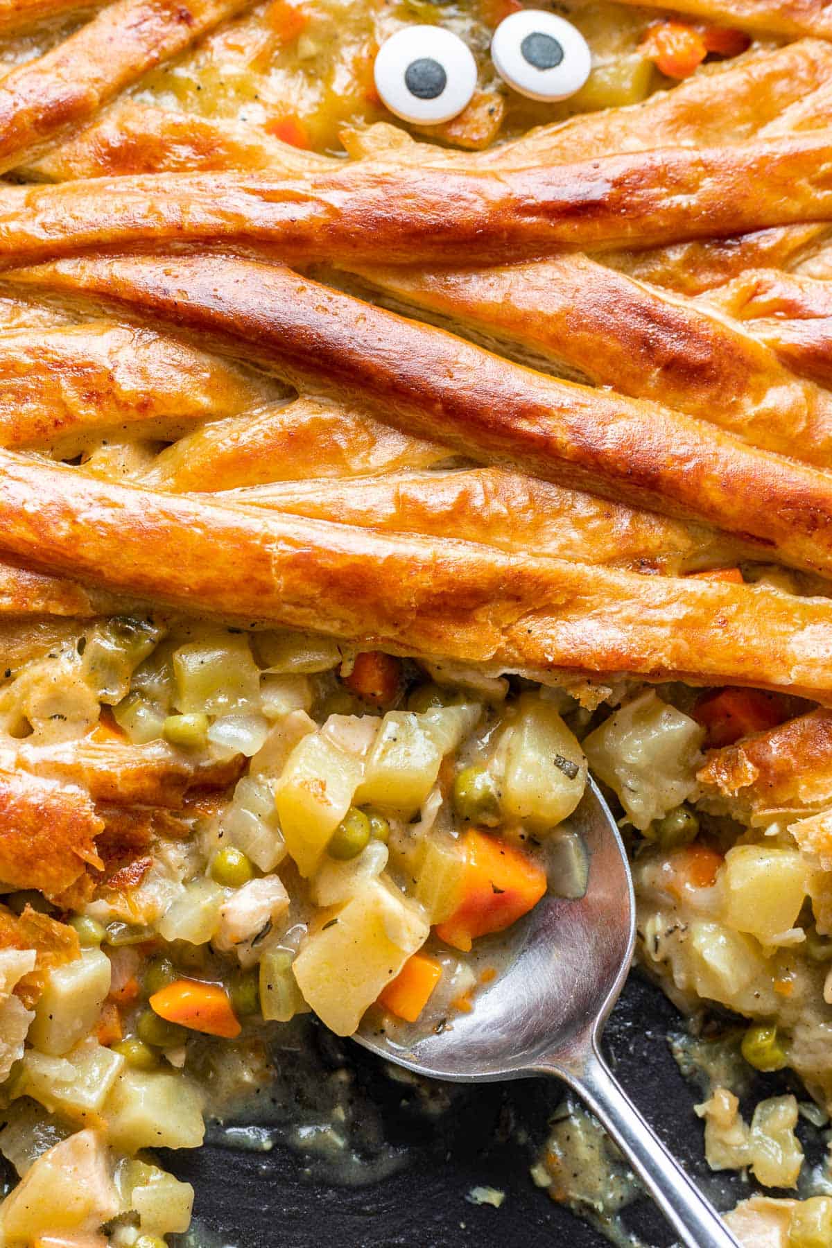 A spoon scooping the filling of mummy chicken pot pie.