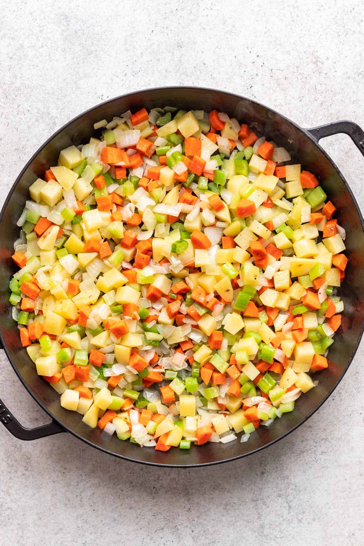 Diced carrots, celery, onions, and potatoes in a large skillet.
