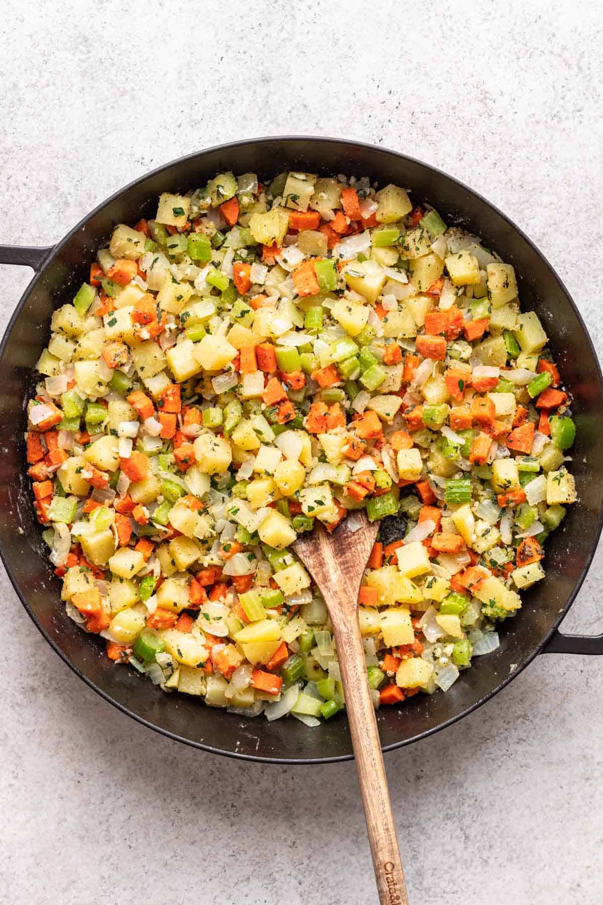 Fresh herbs and seasonings added to veggies in a large skillet.