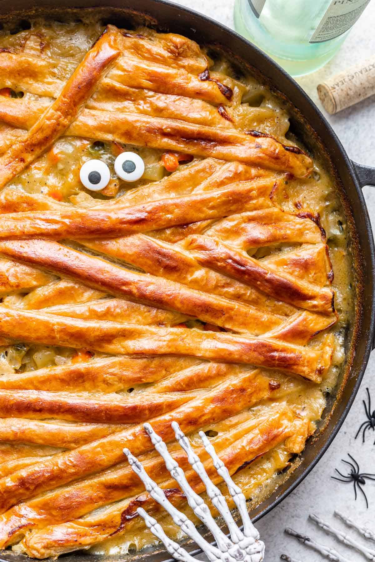 Candy eyes added on top of chicken pot pie in a skillet.