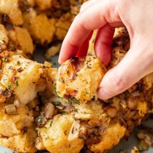 A hand grabbing a piece of savory monkey bread from the rest.
