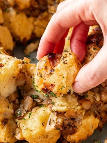 A hand grabbing a piece of savory monkey bread from the rest.