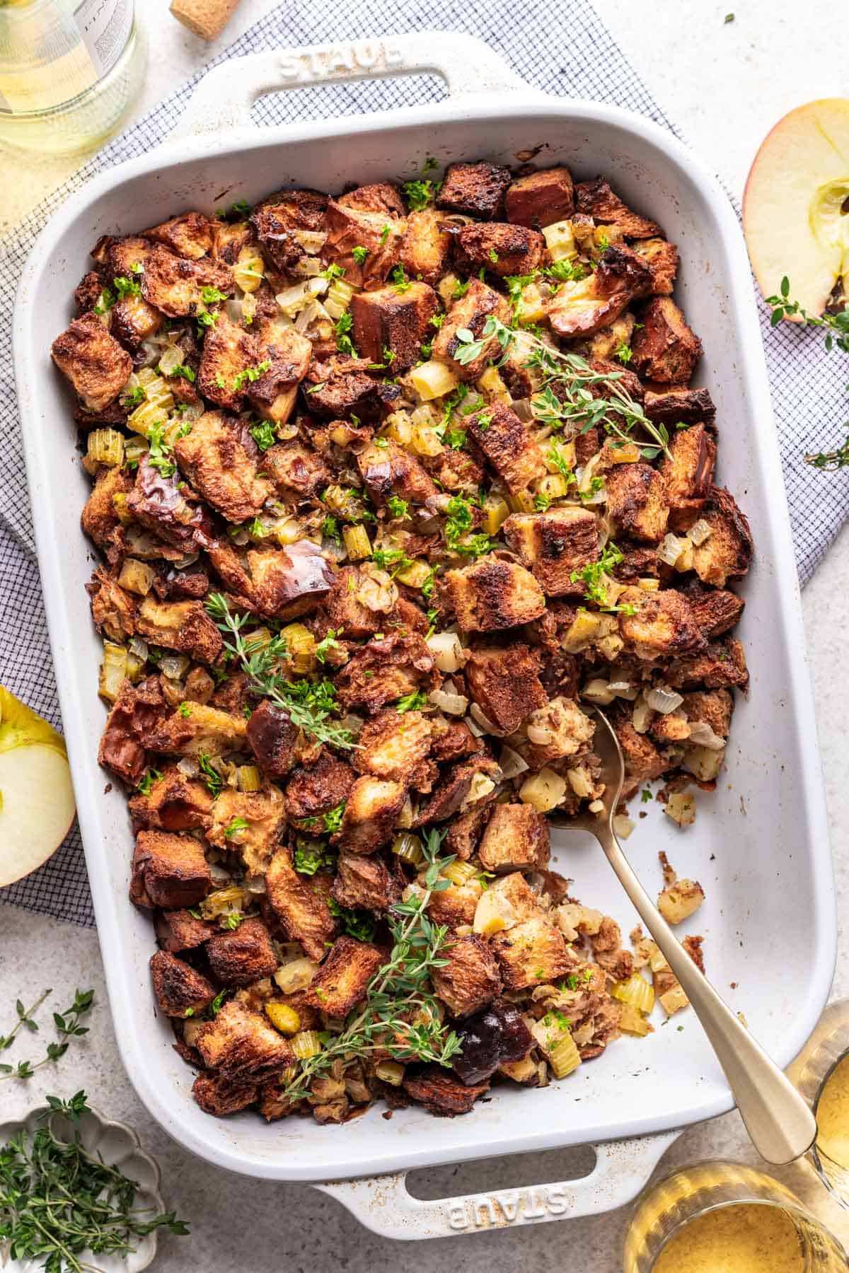 Challah bread Thanksgiving stuffing in a white baking dish with a serving spoon.