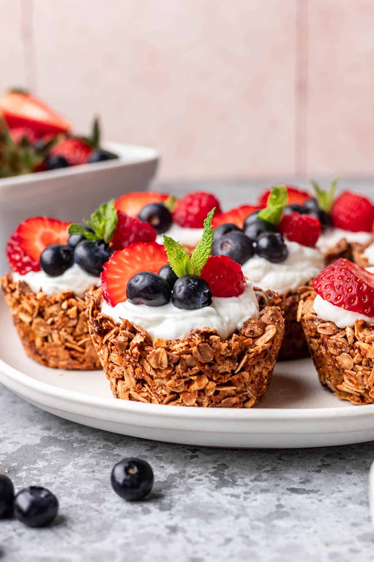 Granola cups topped with greek yogurt, fresh berries, and a sprig of mint.