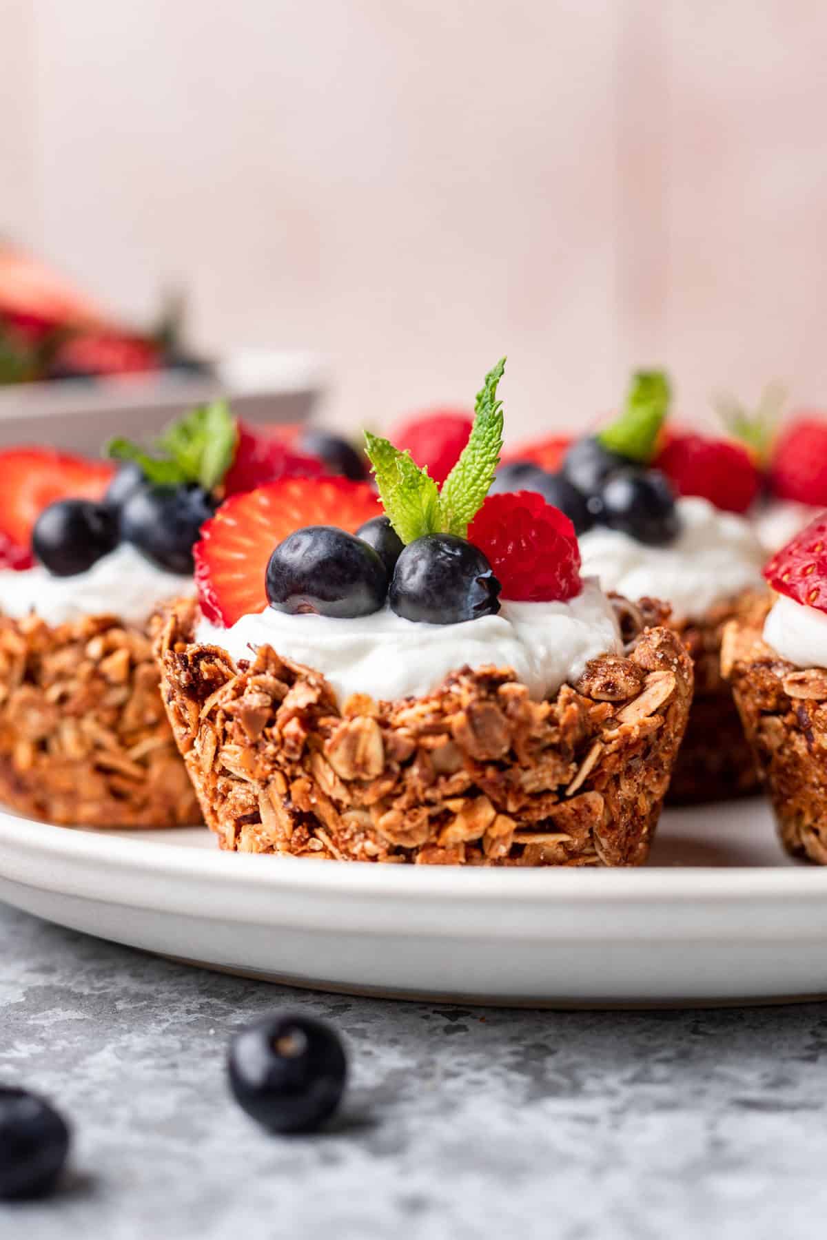 Granola cups filled with greek yogurt and berries on a serving platter.