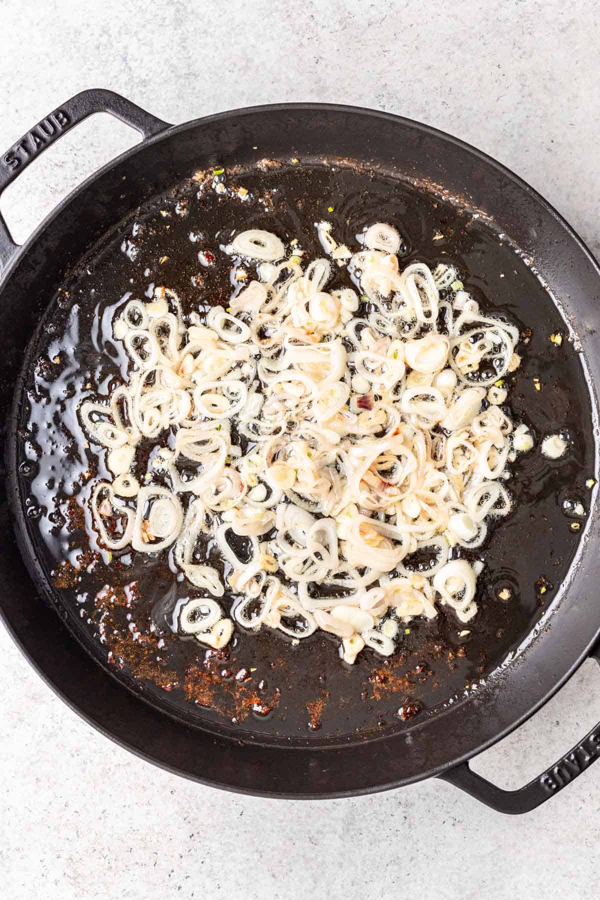 Oil, shallots, and garlic cooked in a skillet.