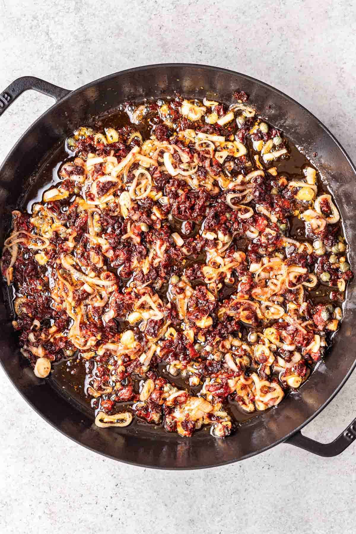 Sun dried tomatoes, tomato paste, capers, and seasonings added to the skillet.