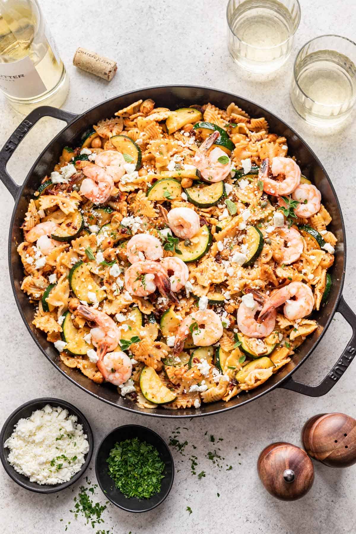 Shrimp and sun dried tomato pasta in a cast iron skillet, garnished with fresh herbs and feta.