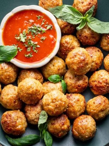 Air fryer chicken meatballs on a green serving platter.