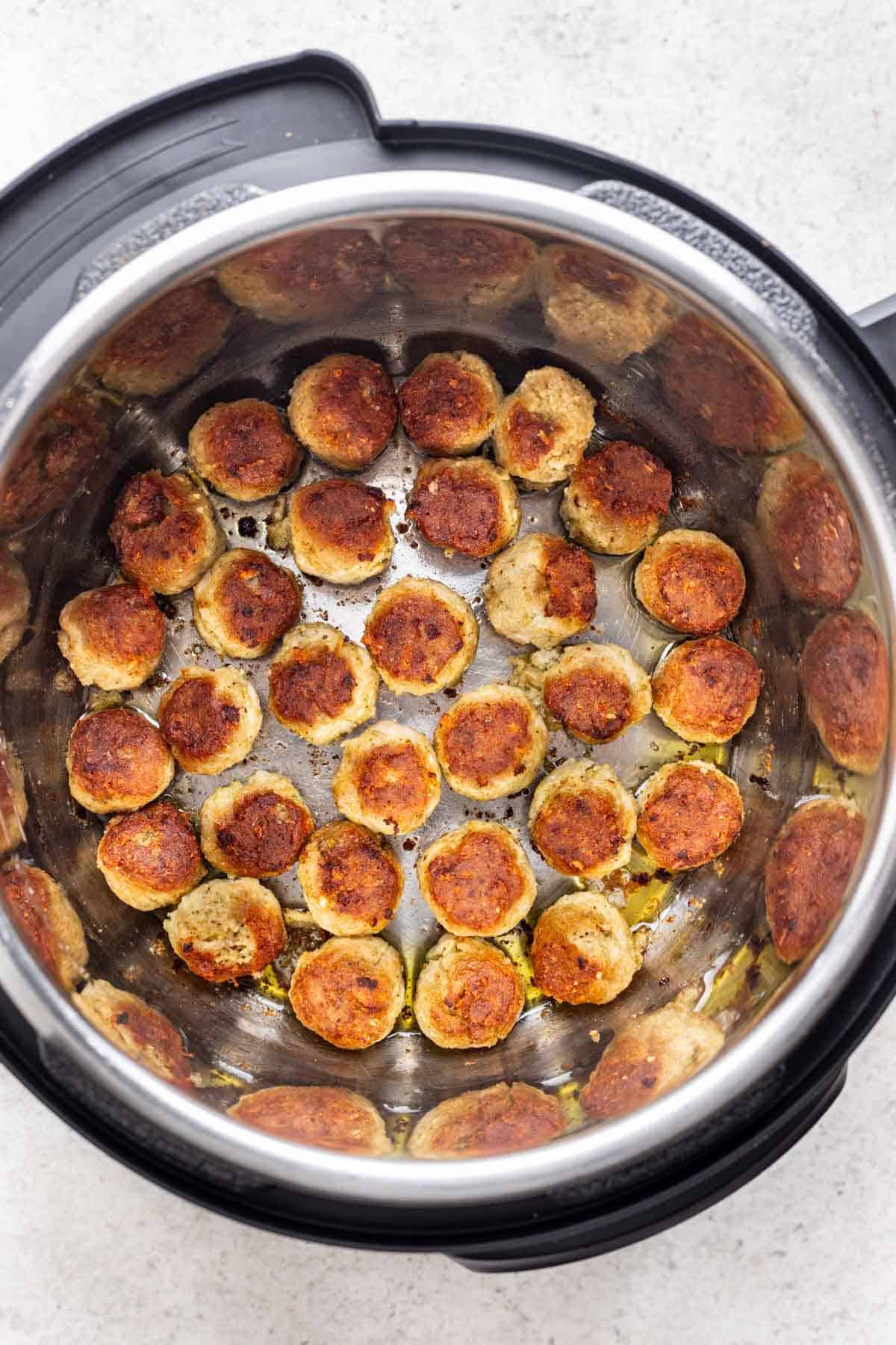 Meatballs cooked in the bottom of an instant pot.