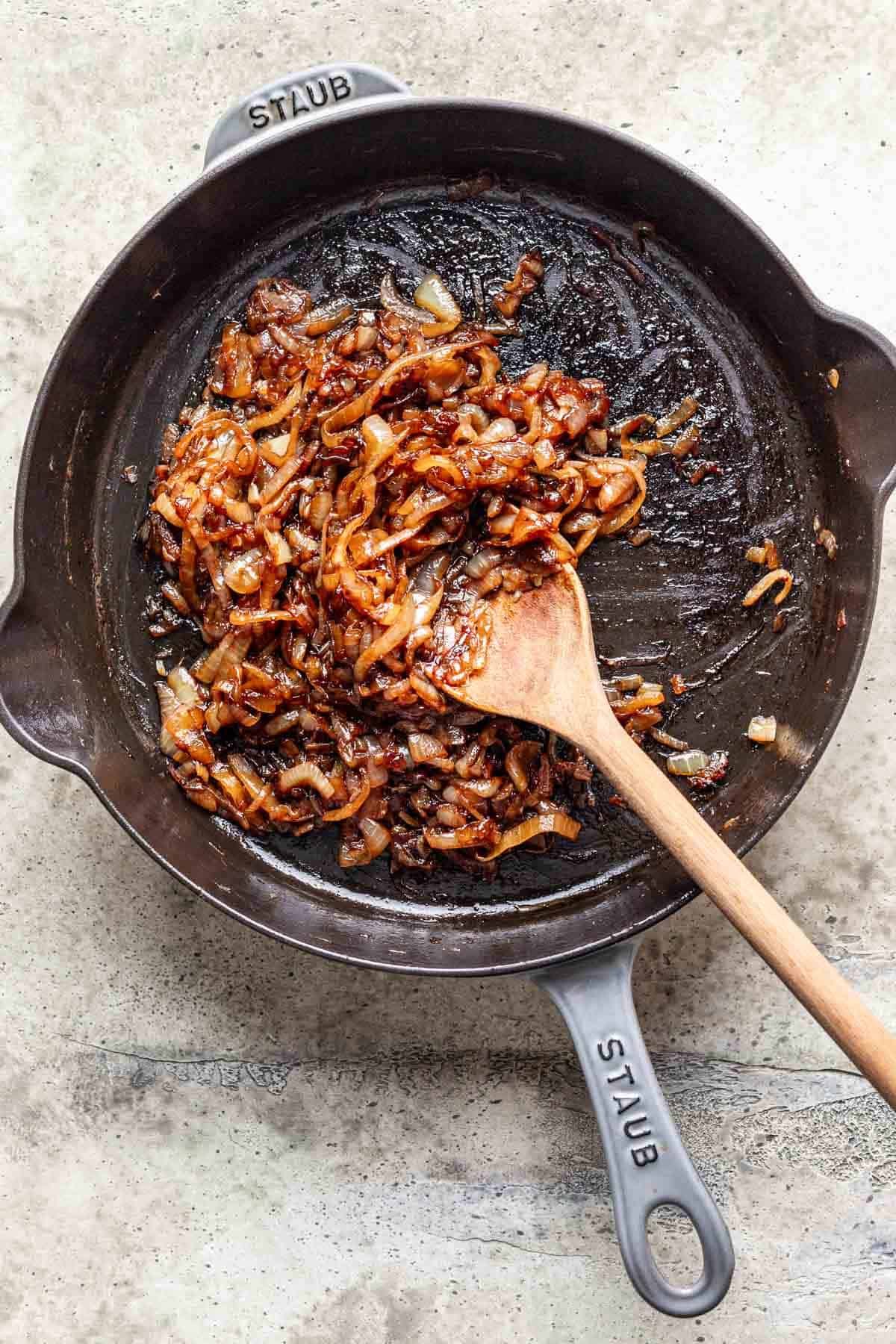Brown sugar, vinegar, and salt added to caramelized onions in a skillet.