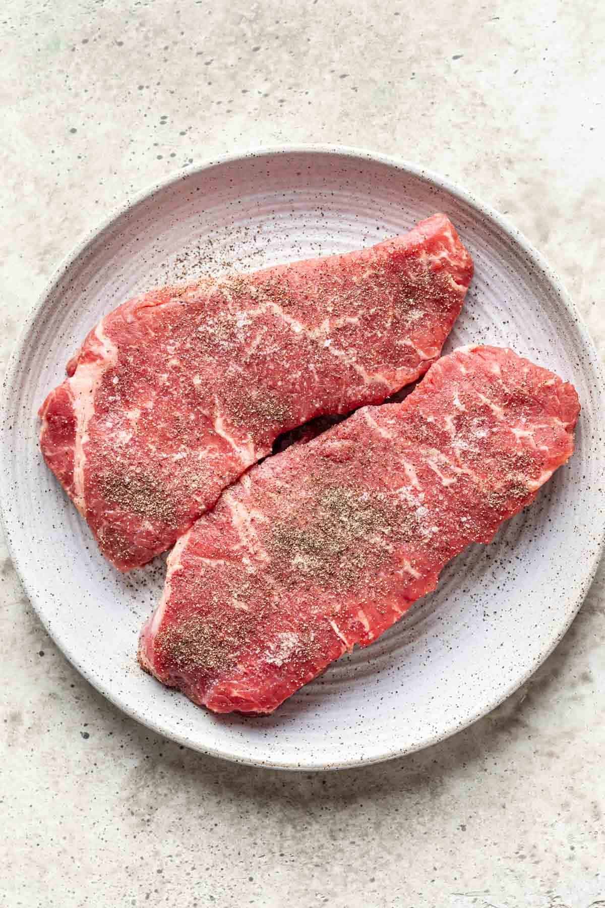 Seasoned steaks on a plate.