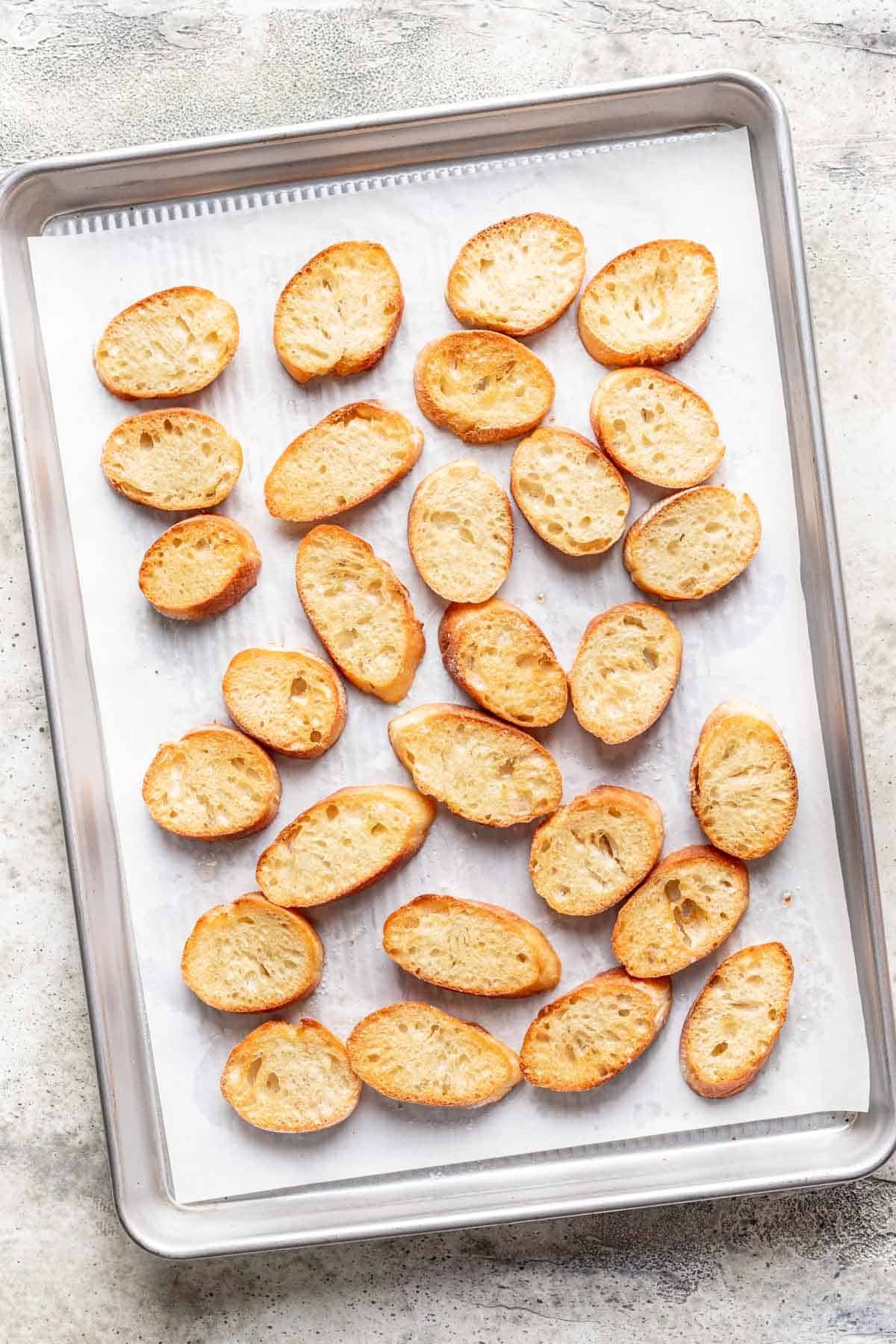 Toasted golden brown french baguette on a baking sheet.
