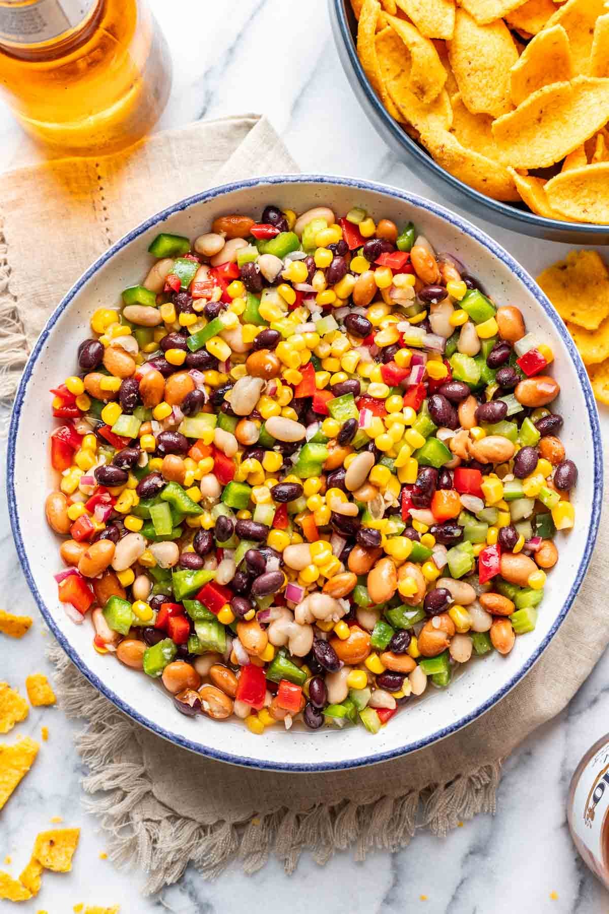 Sweet and Tangy Bean, Corn, and Veggie Dip in a serving bowl with tortilla chips around it.