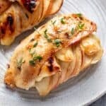 Maple glazed chicken stuffed with apple and brie on a plate.