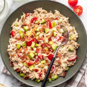 Avocado BLT chicken salad in a green bowl with a serving spoon.
