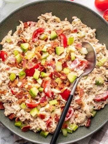 Avocado BLT chicken salad in a green bowl with a serving spoon.