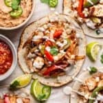 Chicken fajita tacos piled high with all the toppings and a drizzle of sour cream.