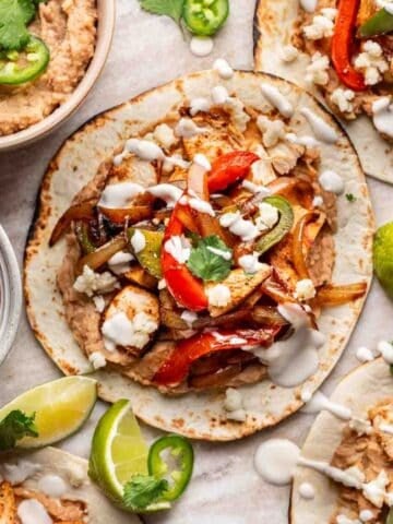 Chicken fajita tacos piled high with all the toppings and a drizzle of sour cream.