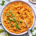 Instant pot Mexican rice in a blue-rimmed serving bowl with a serving spoon.