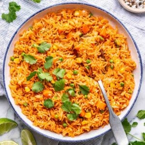 Instant pot Mexican rice in a blue-rimmed serving bowl with a serving spoon.