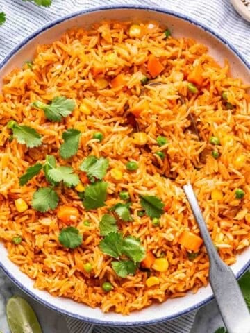 Instant pot Mexican rice in a blue-rimmed serving bowl with a serving spoon.