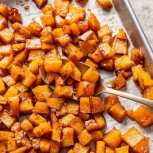 Maple roasted pumpkin on a baking sheet with a serving spoon.