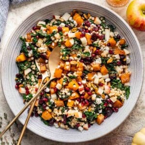 Pumpkin couscous salad in a large serving bowl with serving tongs.