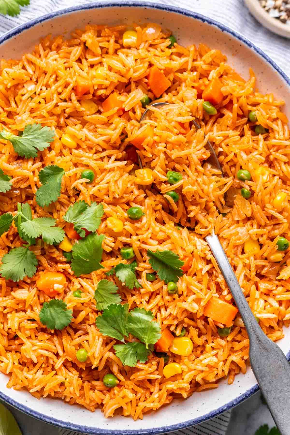 Instant pot Mexican rice with peas, carrots, and corn and garnished with cilantro in a serving bowl.