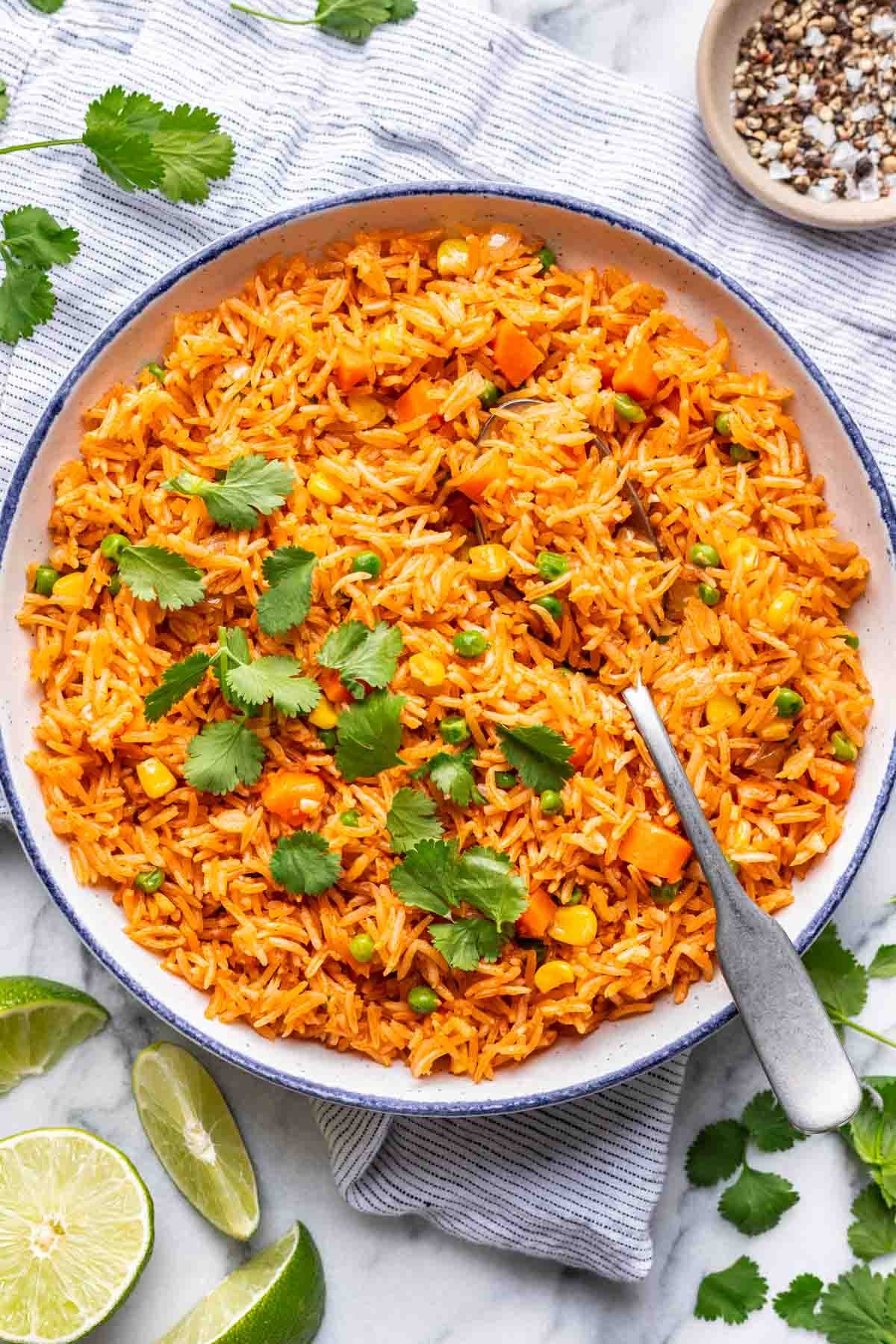 Instant pot Mexican rice in a blue-rimmed serving bowl with a serving spoon.
