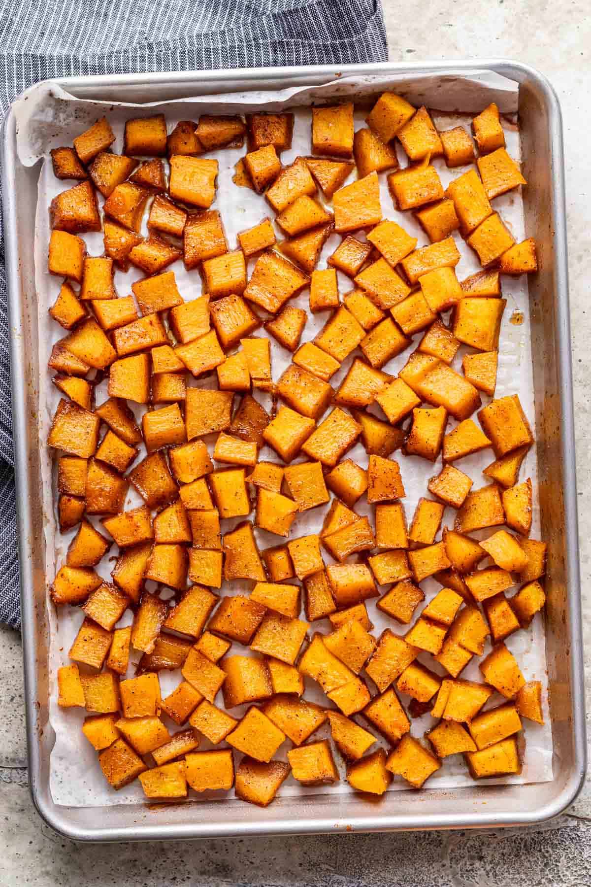 Roasted maple brown sugar pumpkin on a lined baking sheet.
