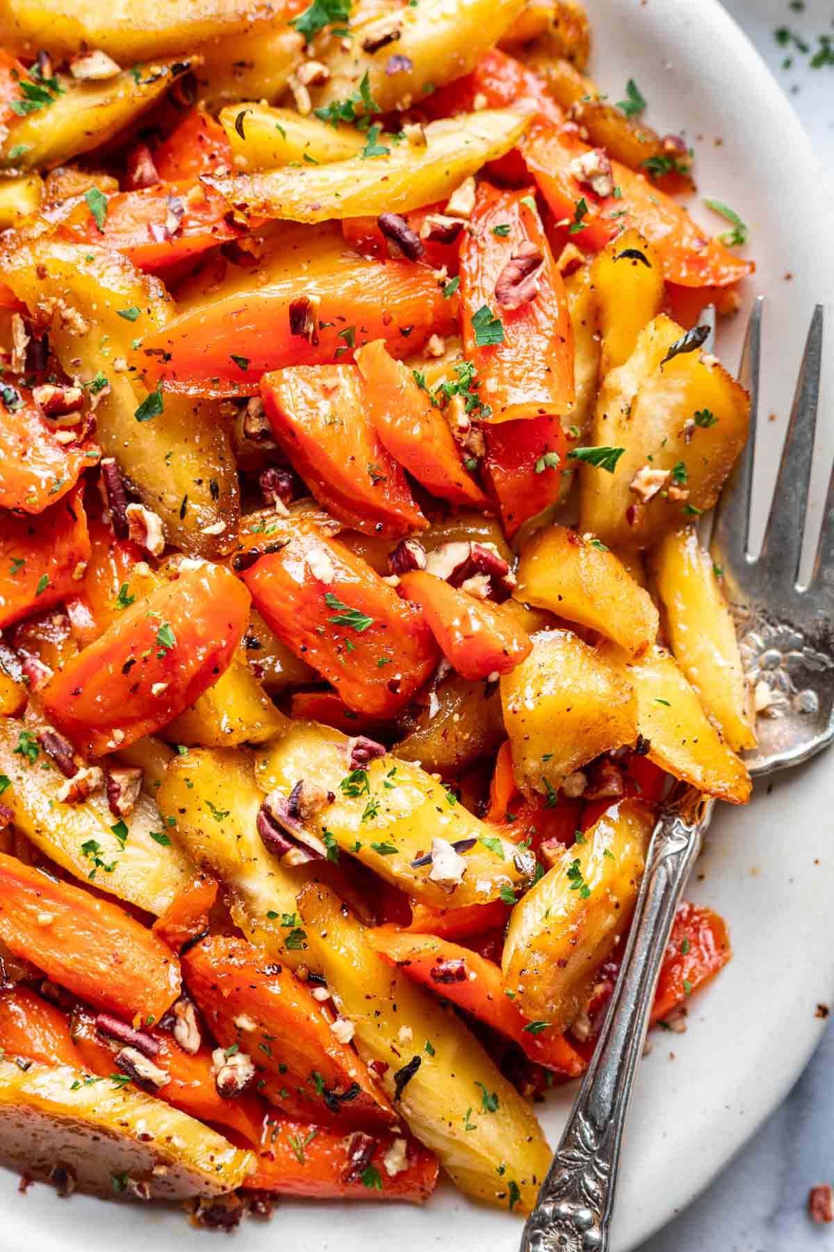 Maple glazed carrots and parsnips on a platter with a serving fork.