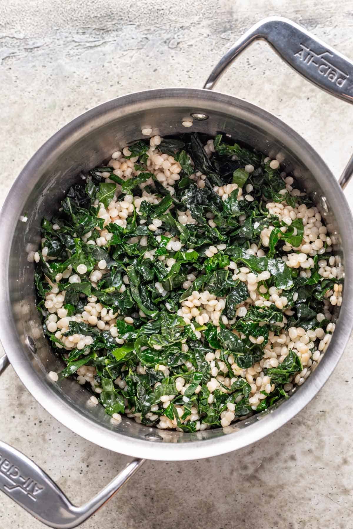 Couscous, kale, and pumpkin dressing mixed together in a pot.